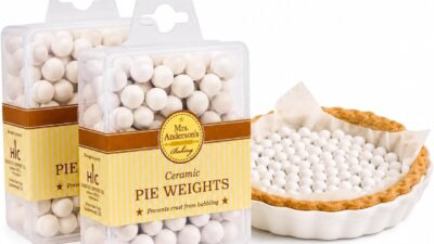 Two boxes of Mrs. Anderson's Baking ceramic pie weights next to a parchment-lined pie crust filled with white ceramic beads