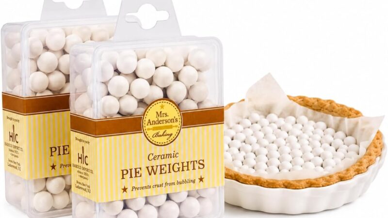 Two boxes of Mrs. Anderson's Baking ceramic pie weights next to a parchment-lined pie crust filled with white ceramic beads