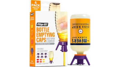 Flip-It bottle emptying caps kit box next to an upside-down hand soap bottle standing on a purple Flip-It cap
