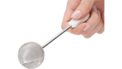 Hand holding an OXO Good Grips baker's dusting wand with a stainless steel mesh ball